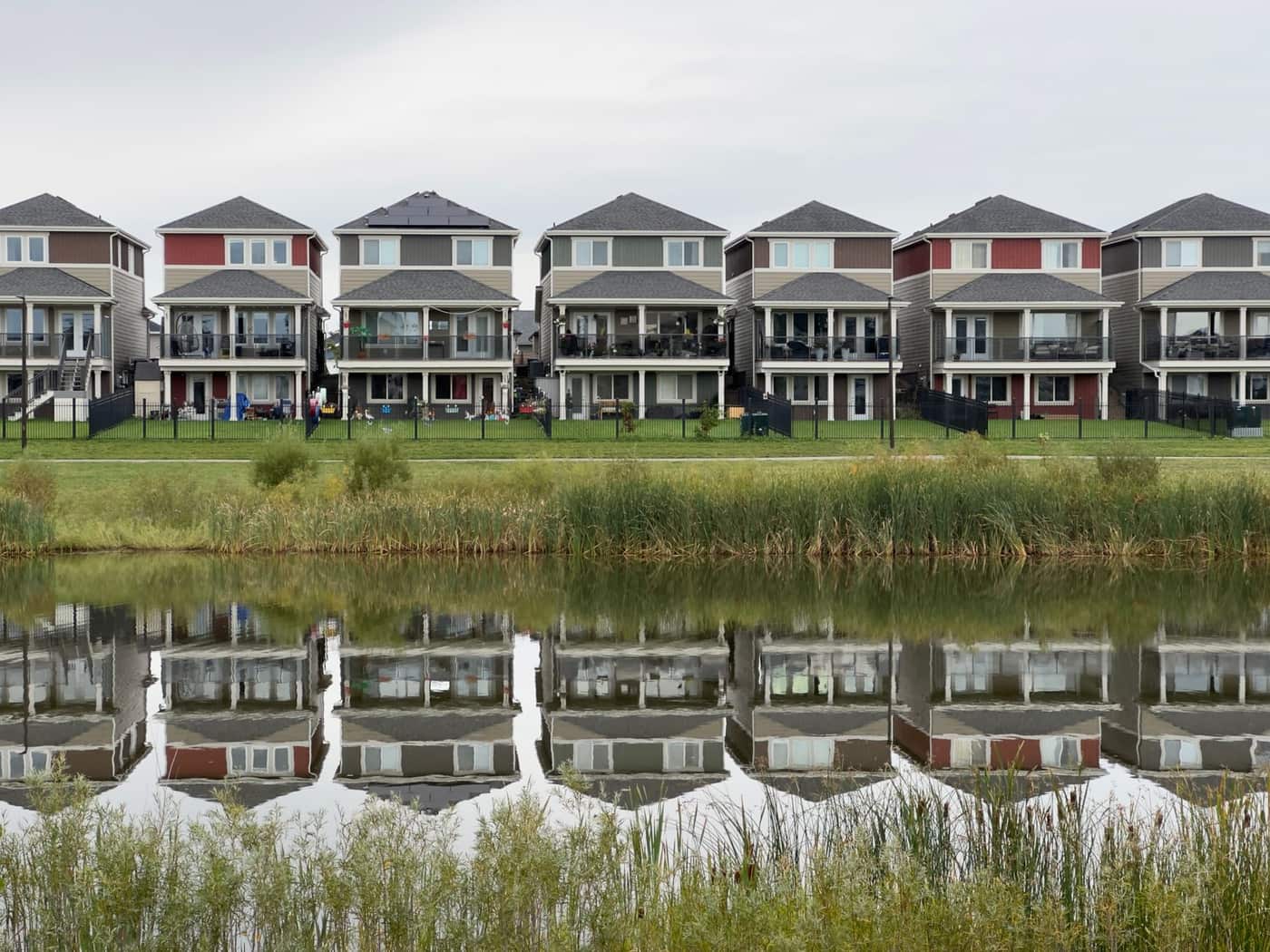 A row of modern houses reflected in a calm pond in a residential development