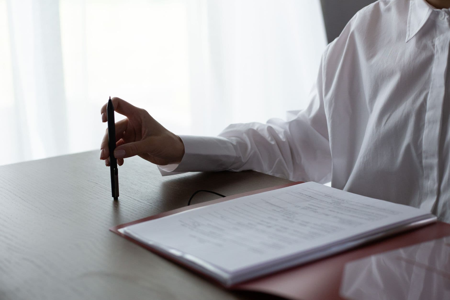 A woman reviewing paperwork with a pen at a desk in an office setting