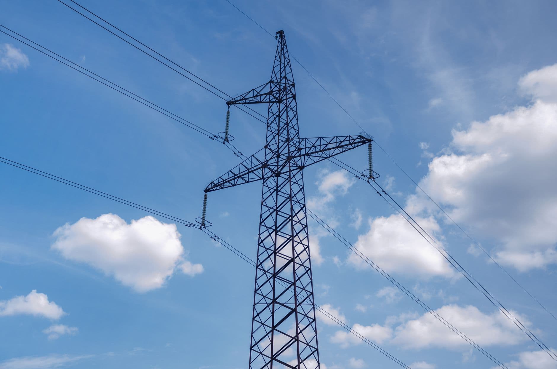 A high-voltage electricity transmission tower against a blue sky