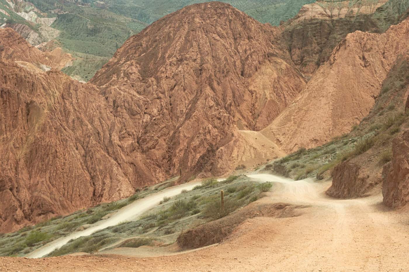 A dirt road cutting through a rugged, mountainous landscape