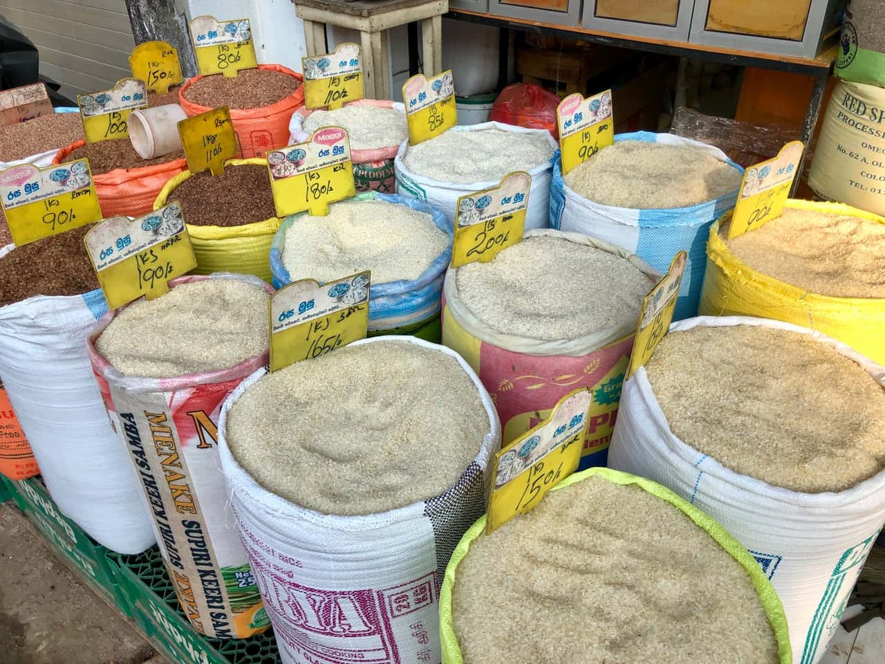 Sacks of different grains with price tags on display at a market stall