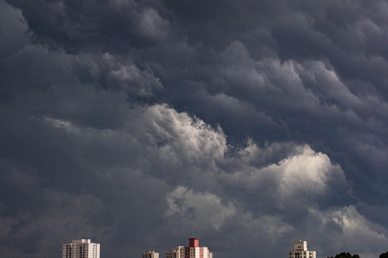 Dark storm clouds looming over city buildings in a dramatic, rain-heavy sky