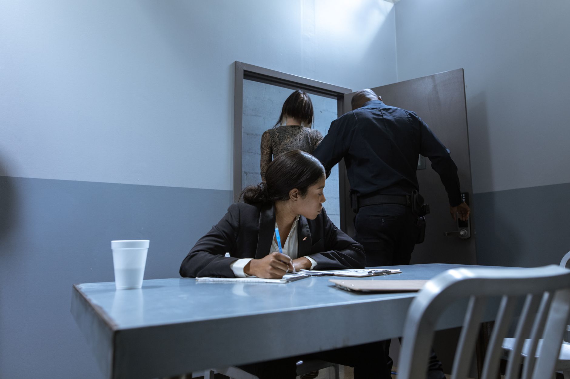 Police officer escorting a suspect while a lawyer observes during an interrogation