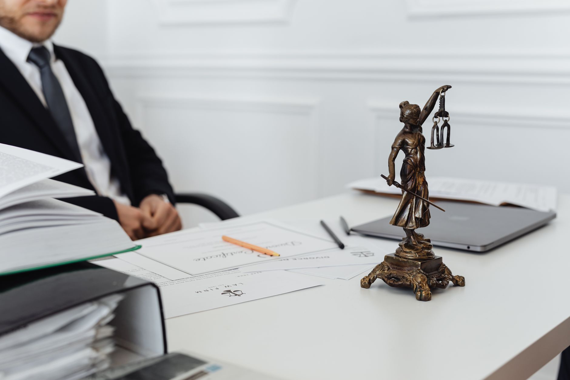 A lawyer's desk with a Lady Justice statue, legal documents and a laptop