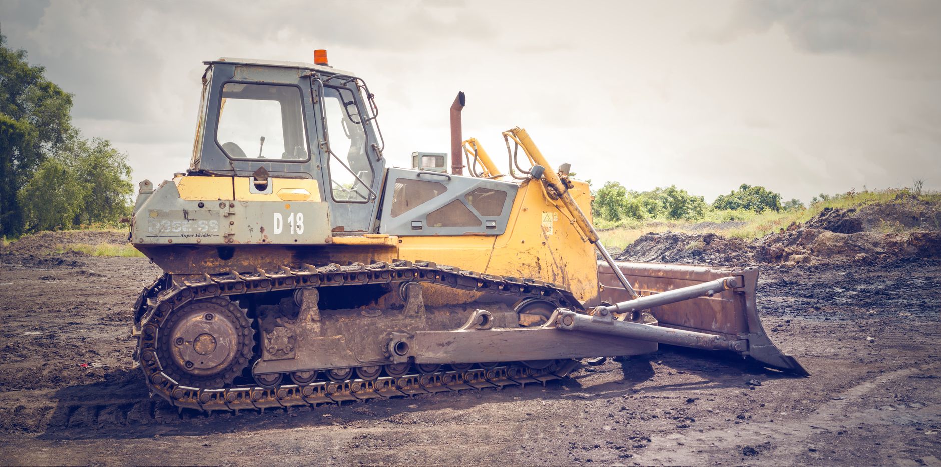 A bulldozer on a dirt construction site under a cloudy sky