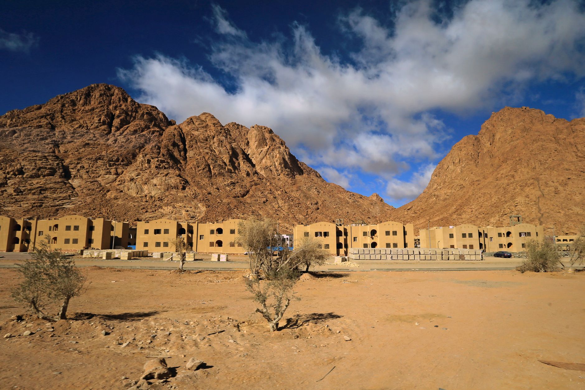 A town at the base of rocky mountains with an arid desert landscape under blue skies