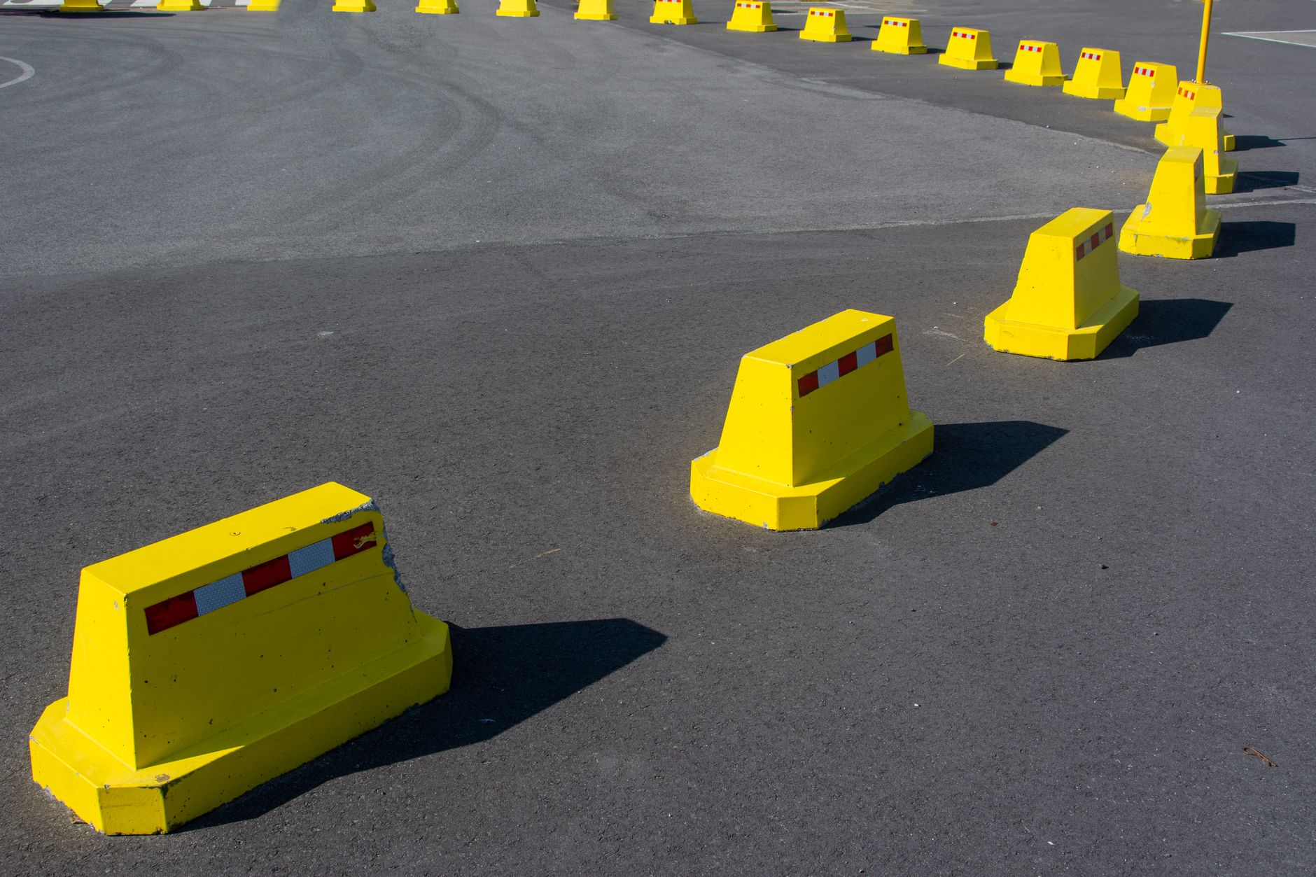 Row of bright yellow traffic barriers on an empty asphalt road