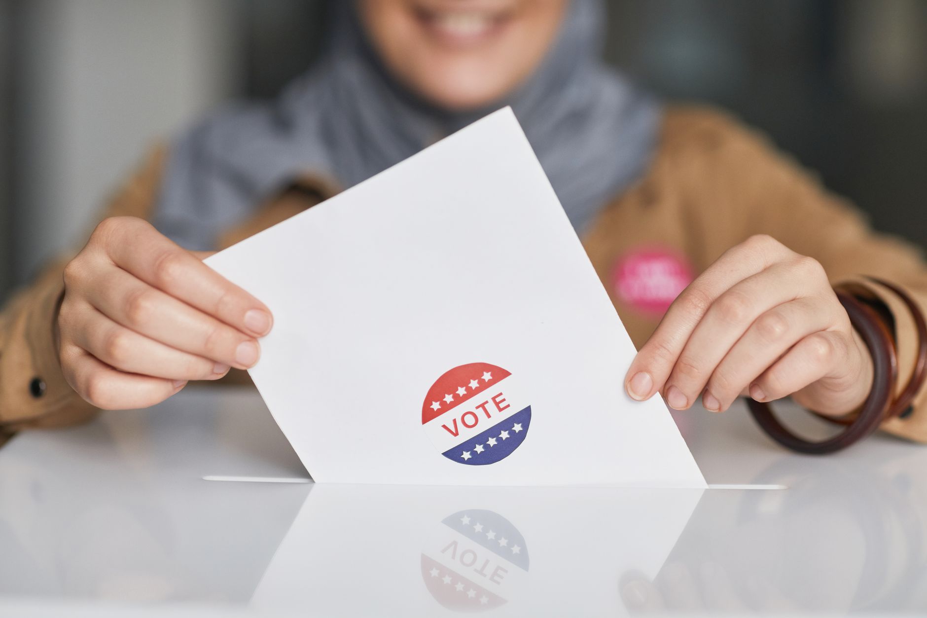 Close-up of hands holding and casting a vote ballot
