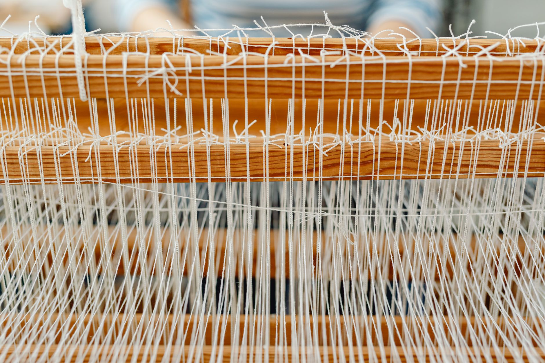 Detailed close-up of a wooden loom with white threads, showcasing traditional weaving