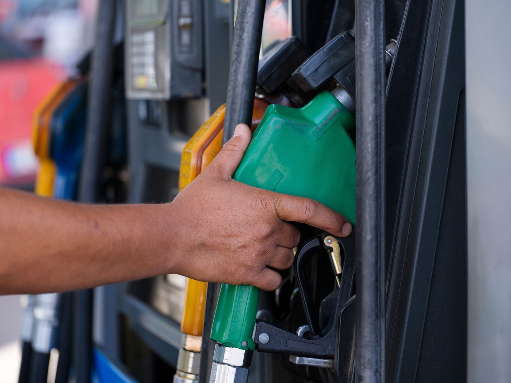 Close-up of a hand holding a fuel pump nozzle at a gas station