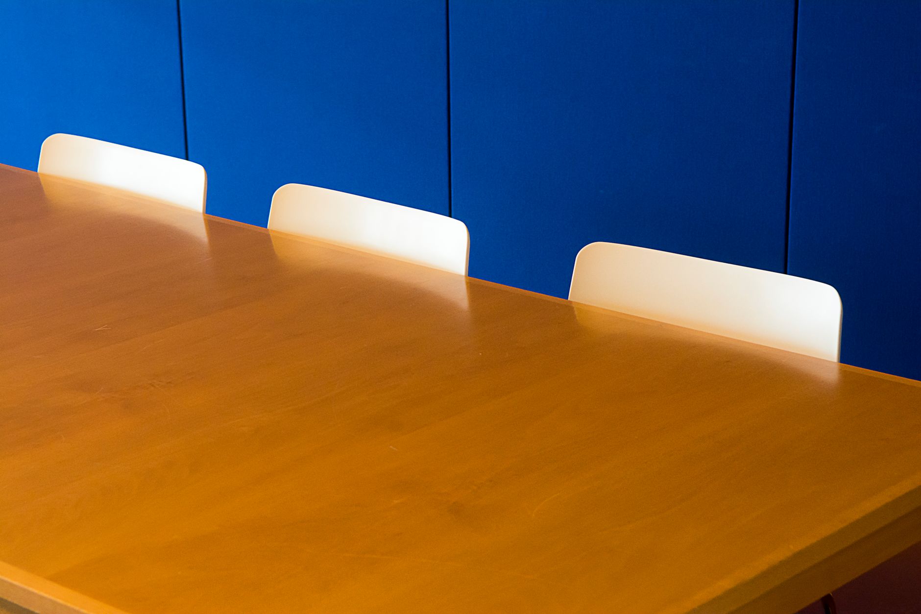A clean and modern indoor meeting room with a wooden table against a blue wall