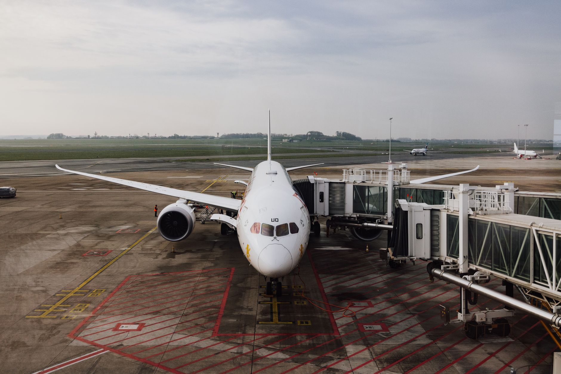 A modern jet airplane docked at an airport terminal gate on a cloudy day