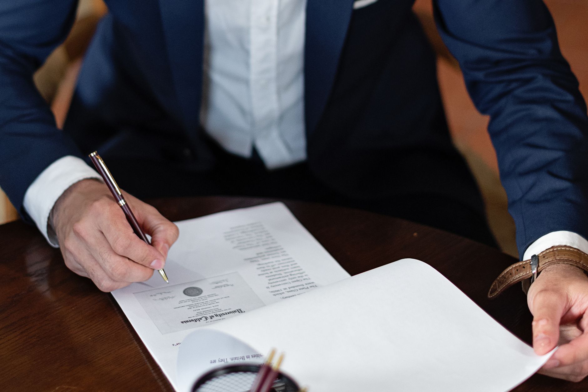 A professional signing legal documents at a desk in an office setting