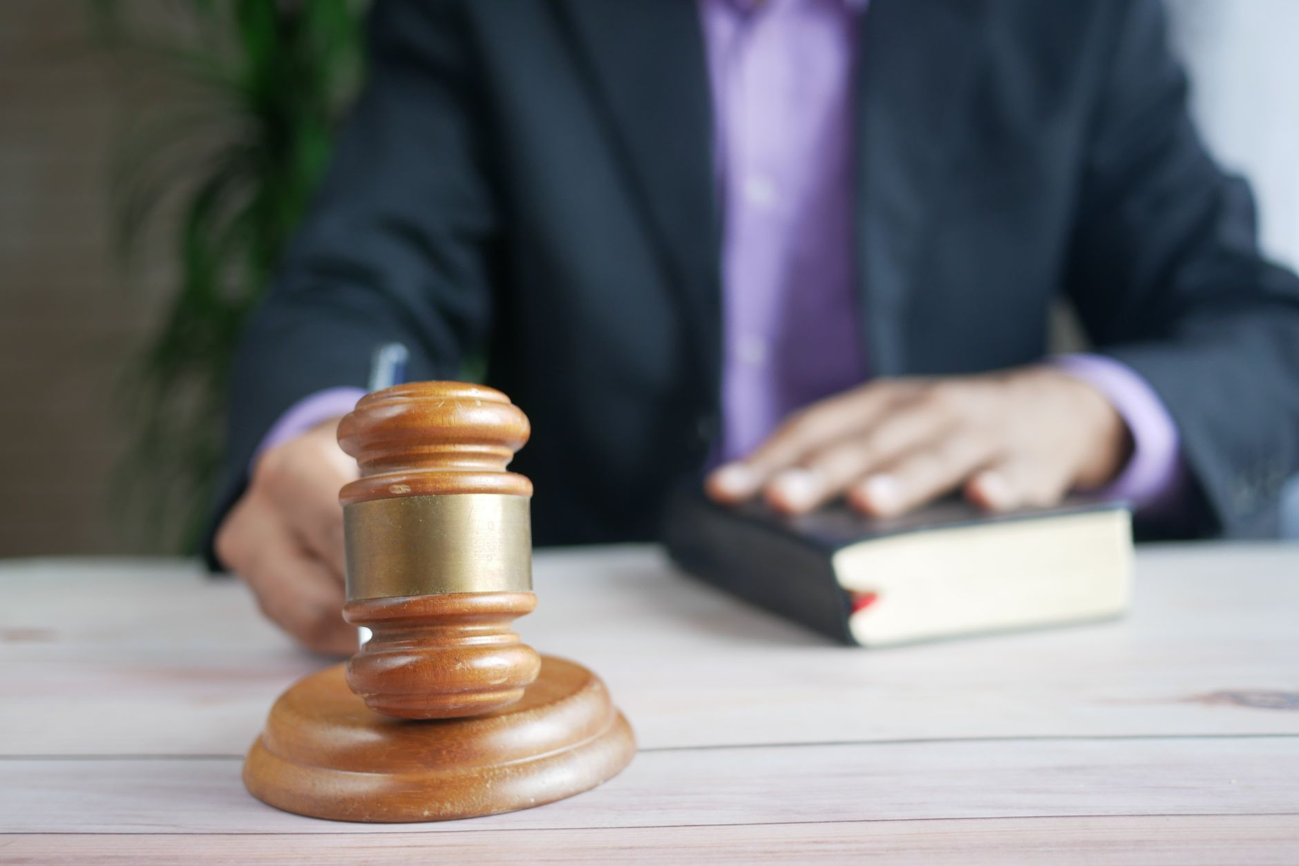 A wooden gavel resting on a legal book on a courtroom desk