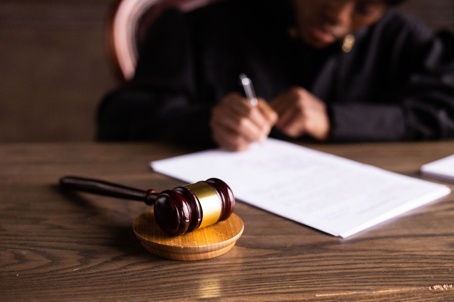 A judge signing documents at a desk with a gavel in the foreground