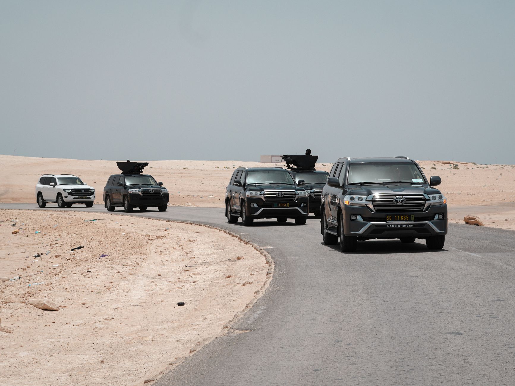A convoy of armored vehicles traveling along a desert road