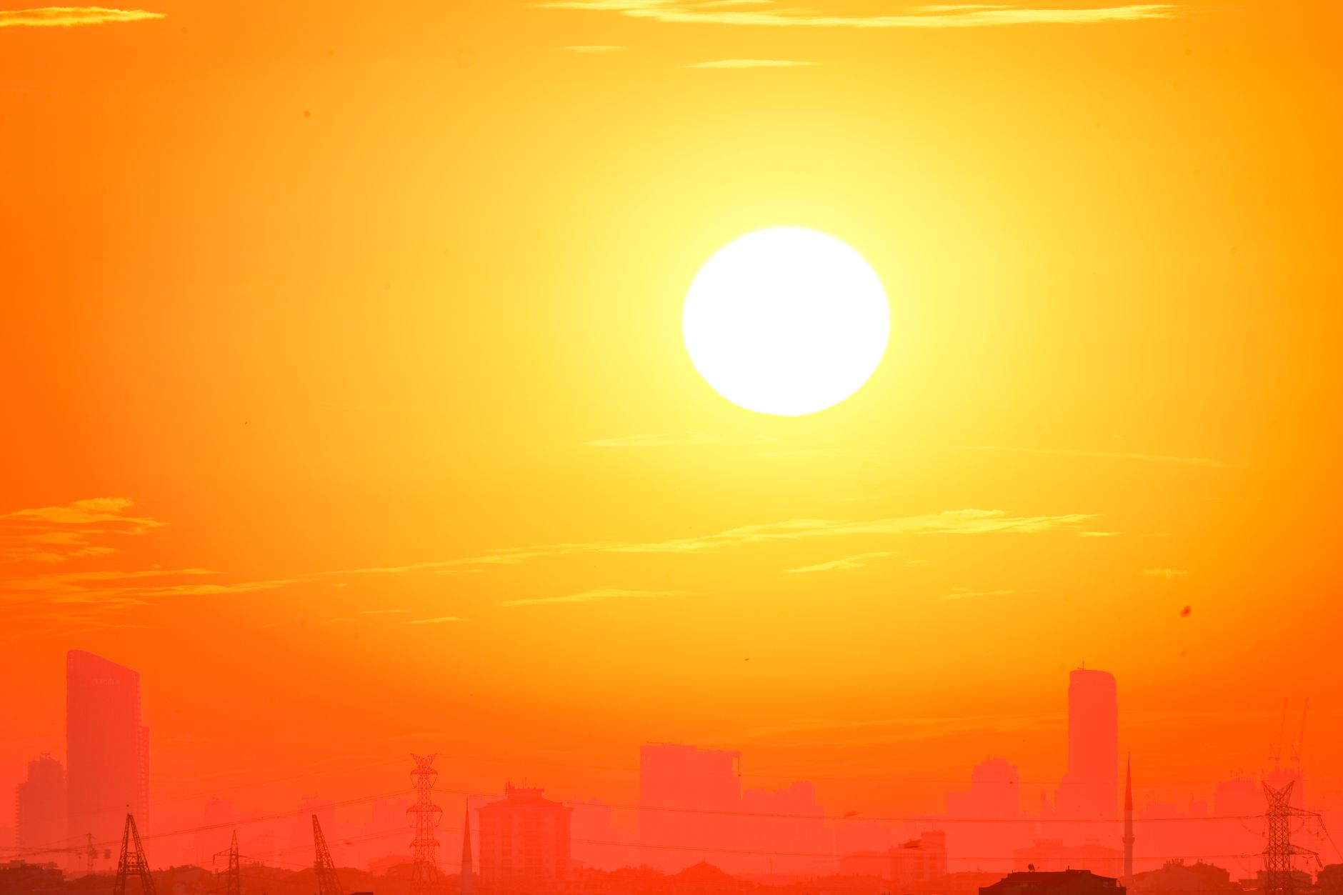A city skyline silhouetted against a vivid orange sunset