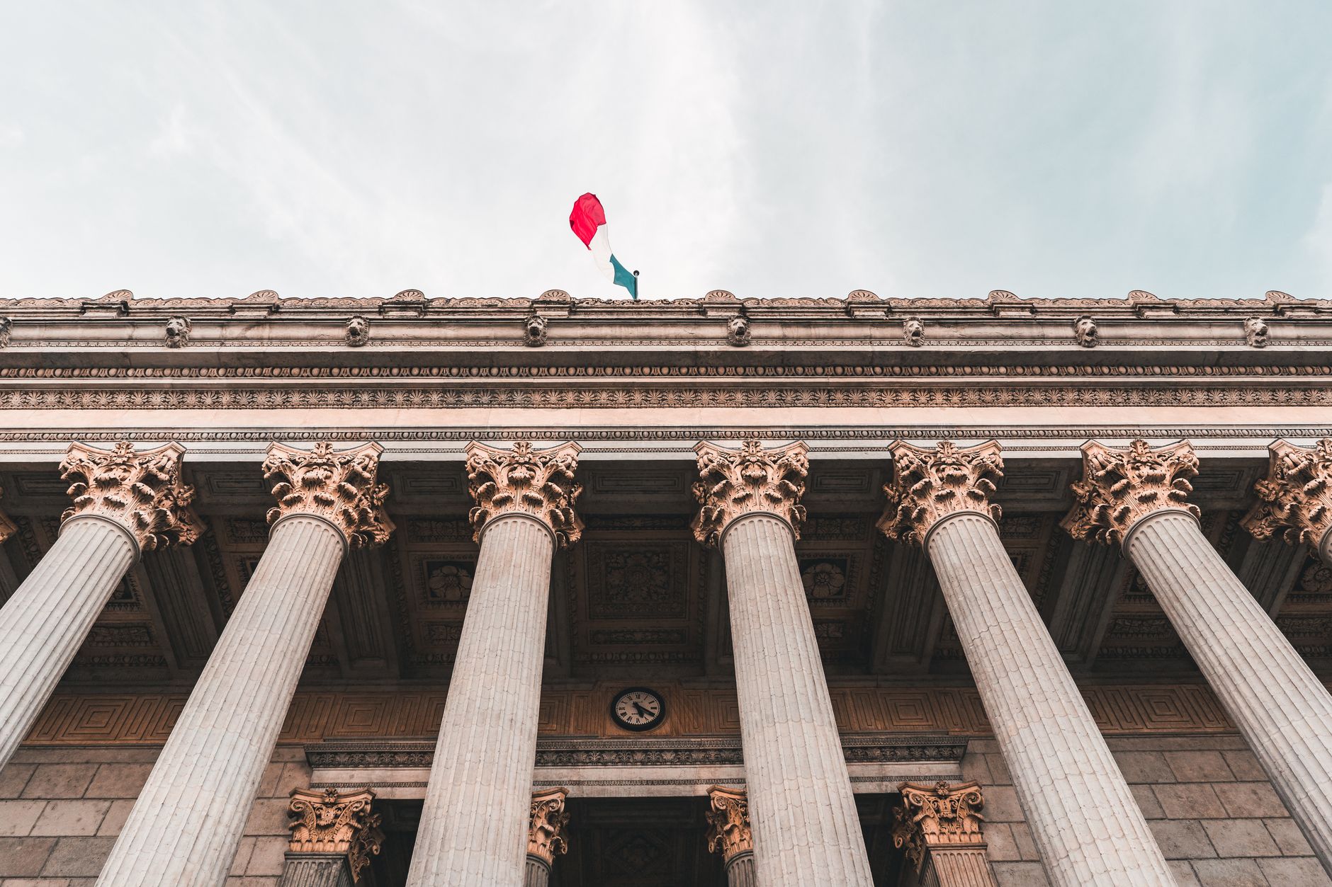 Classical government building facade with columns and a flag against the sky