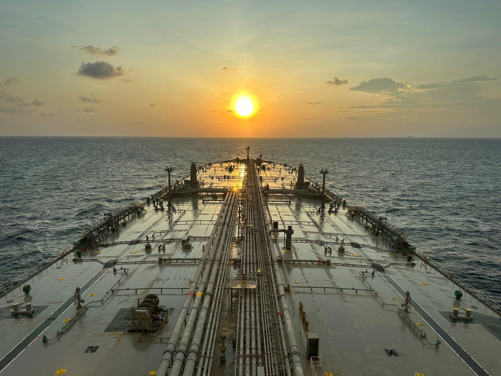 A large oil tanker sailing on the open ocean at sunset