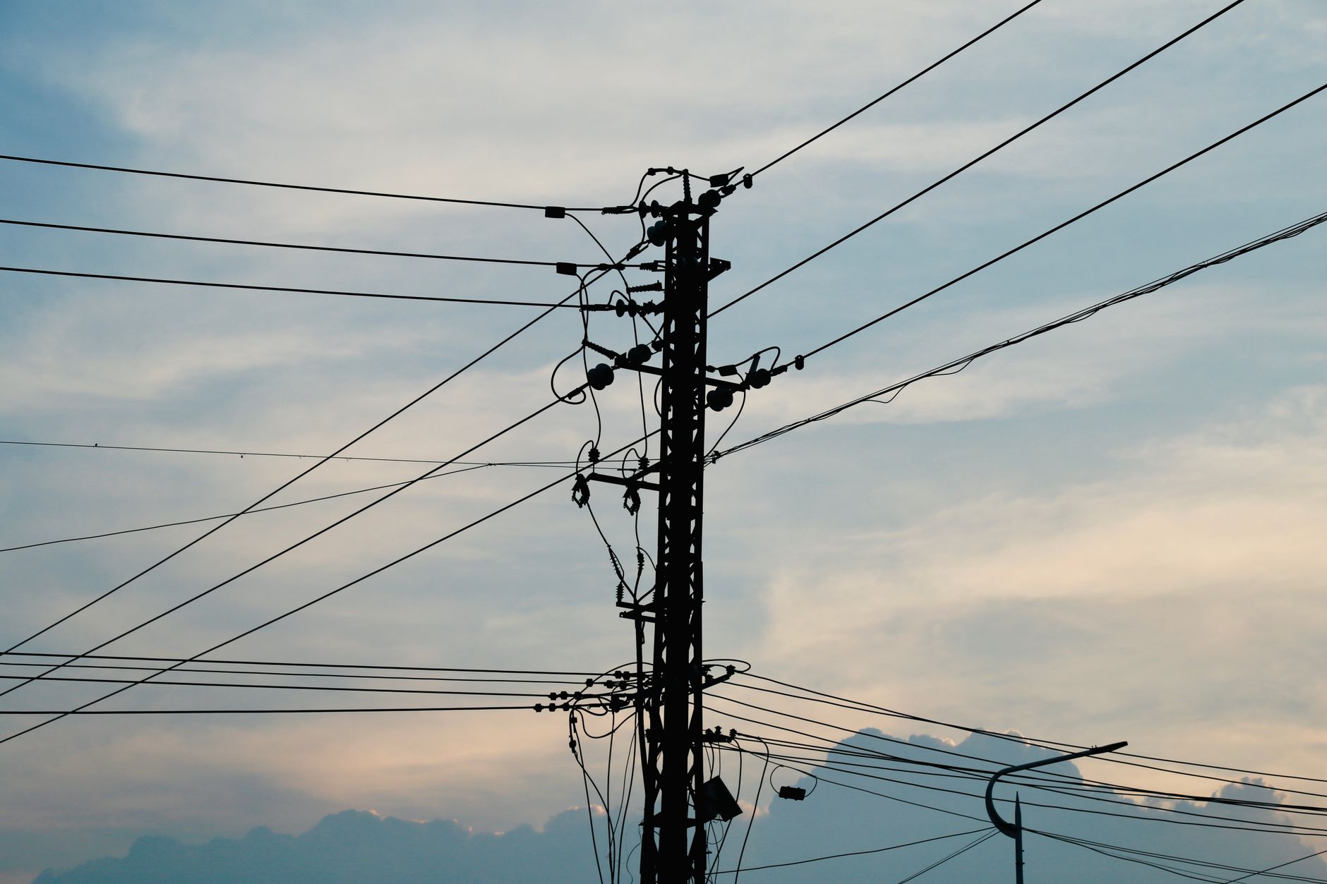 Silhouette of power lines and an electricity pole against a vibrant sunset sky