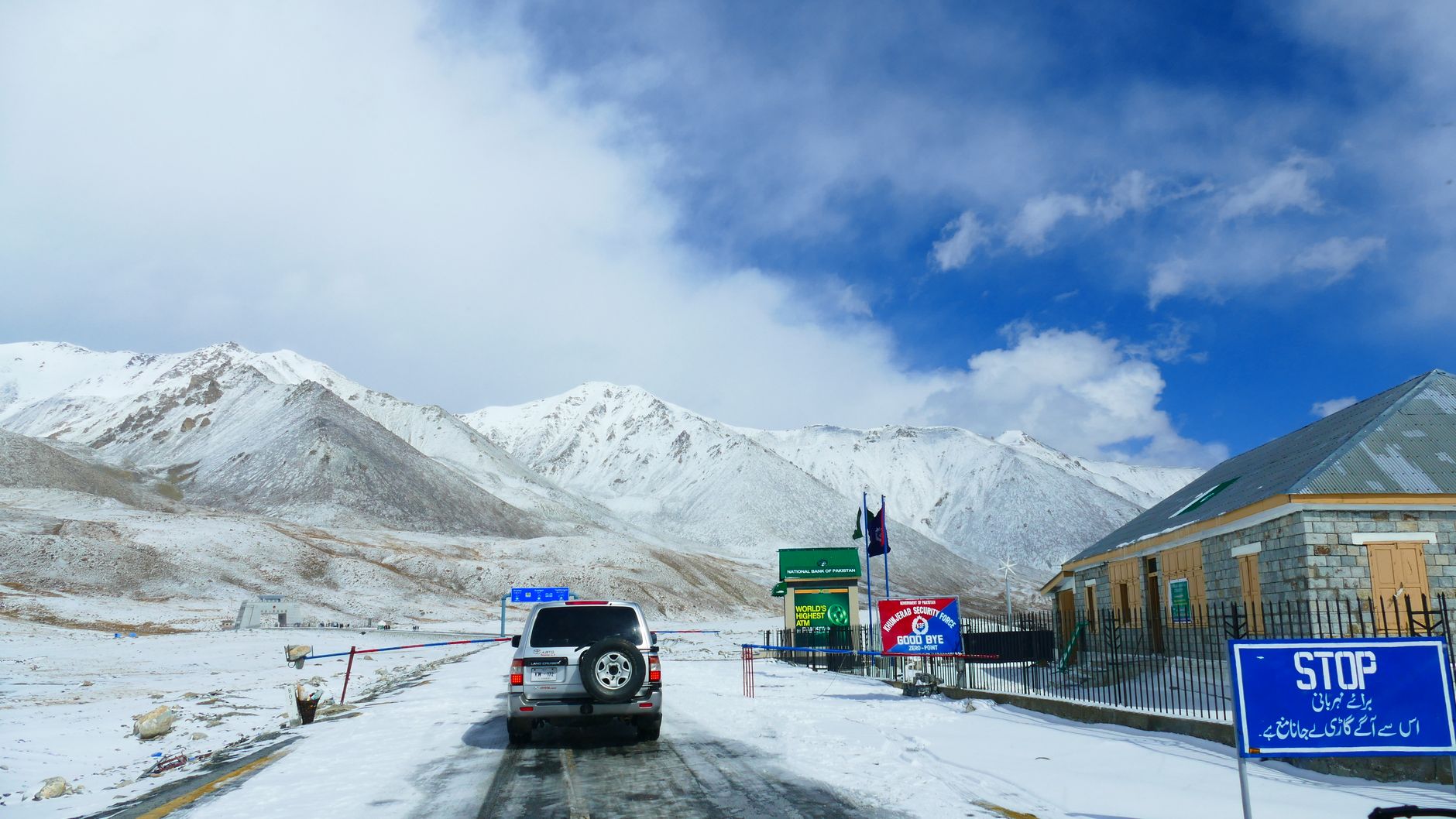 A vehicle approaching a snow-covered mountain border pass