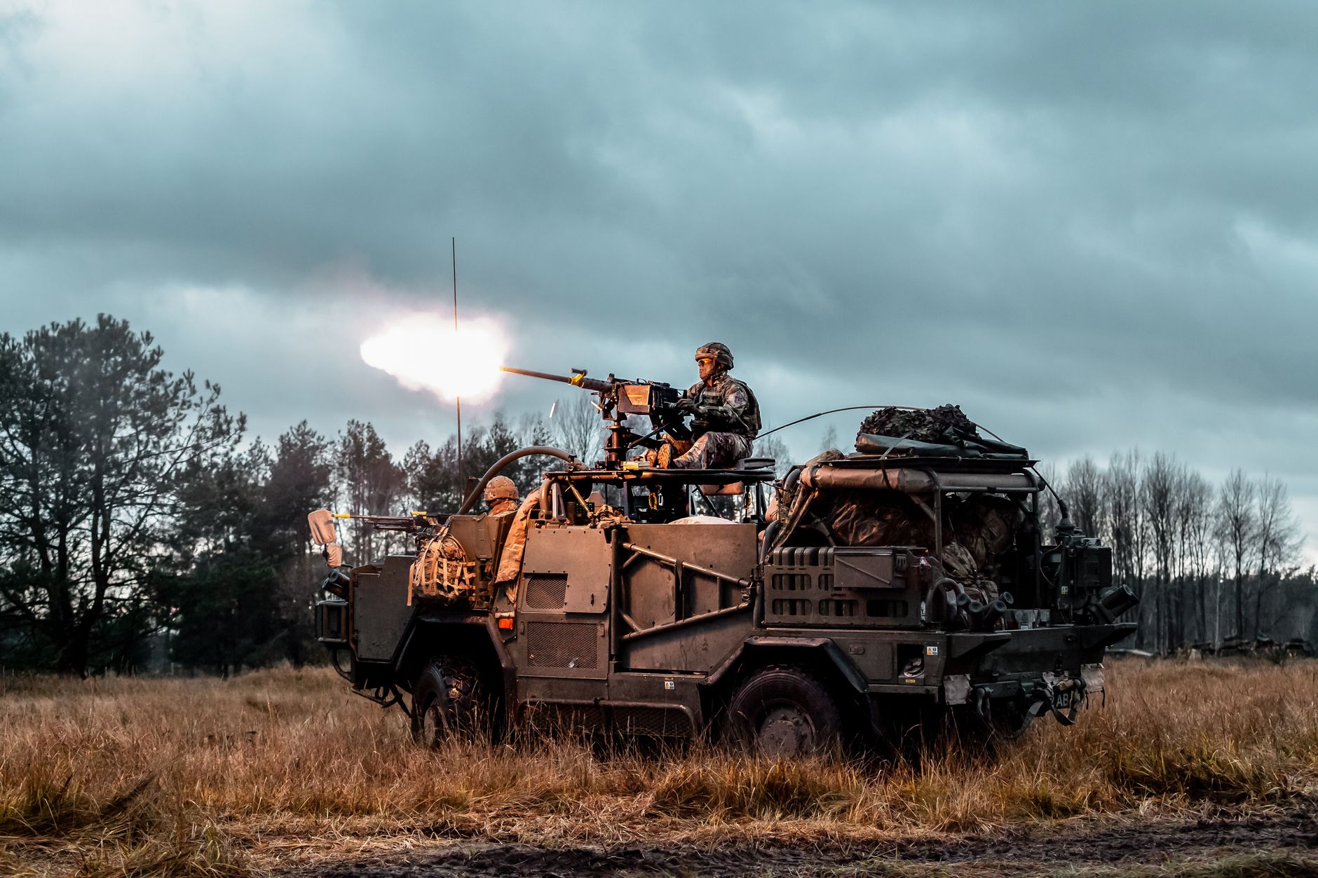A soldier operating a mounted weapon on a military vehicle during an outdoor exercise
