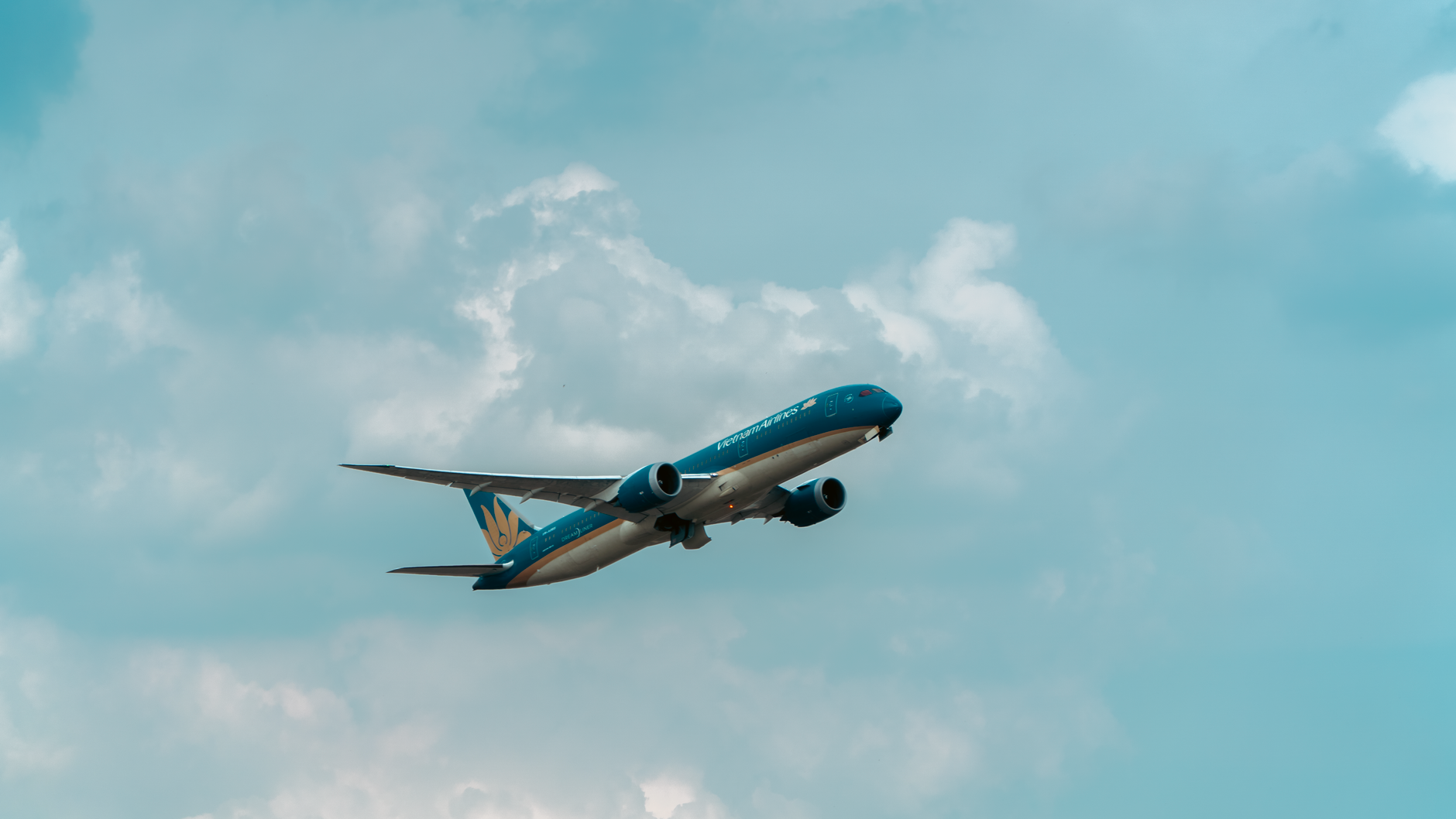 A commercial airplane flying through a cloudy blue sky