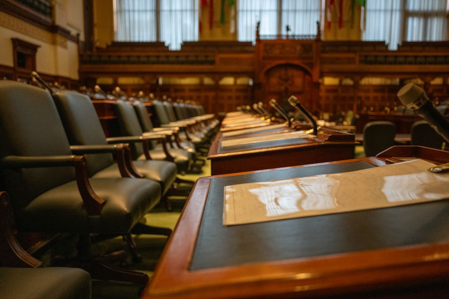 Empty legislative assembly chamber with rows of desks and microphones