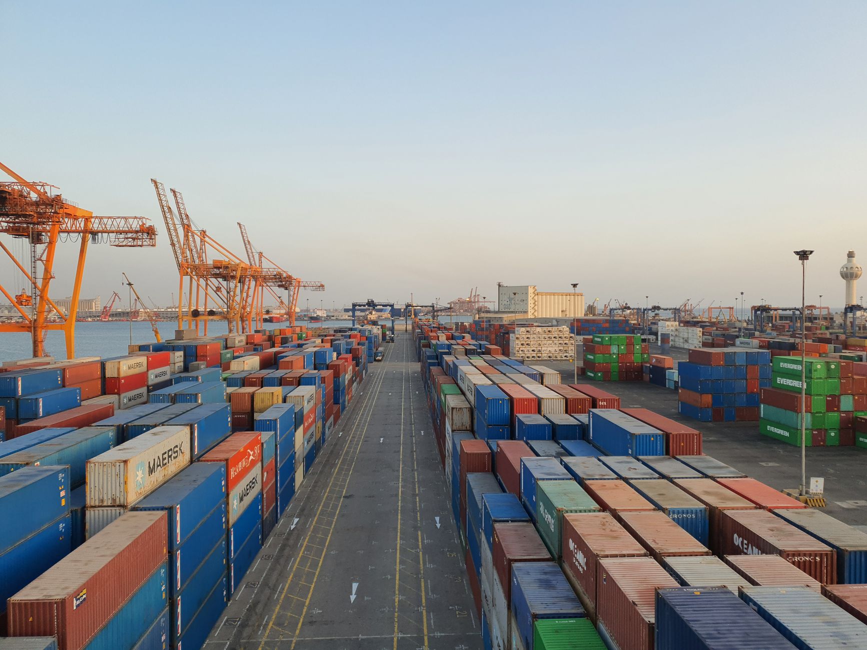 A bustling port scene with colourful cargo containers stacked at sunrise
