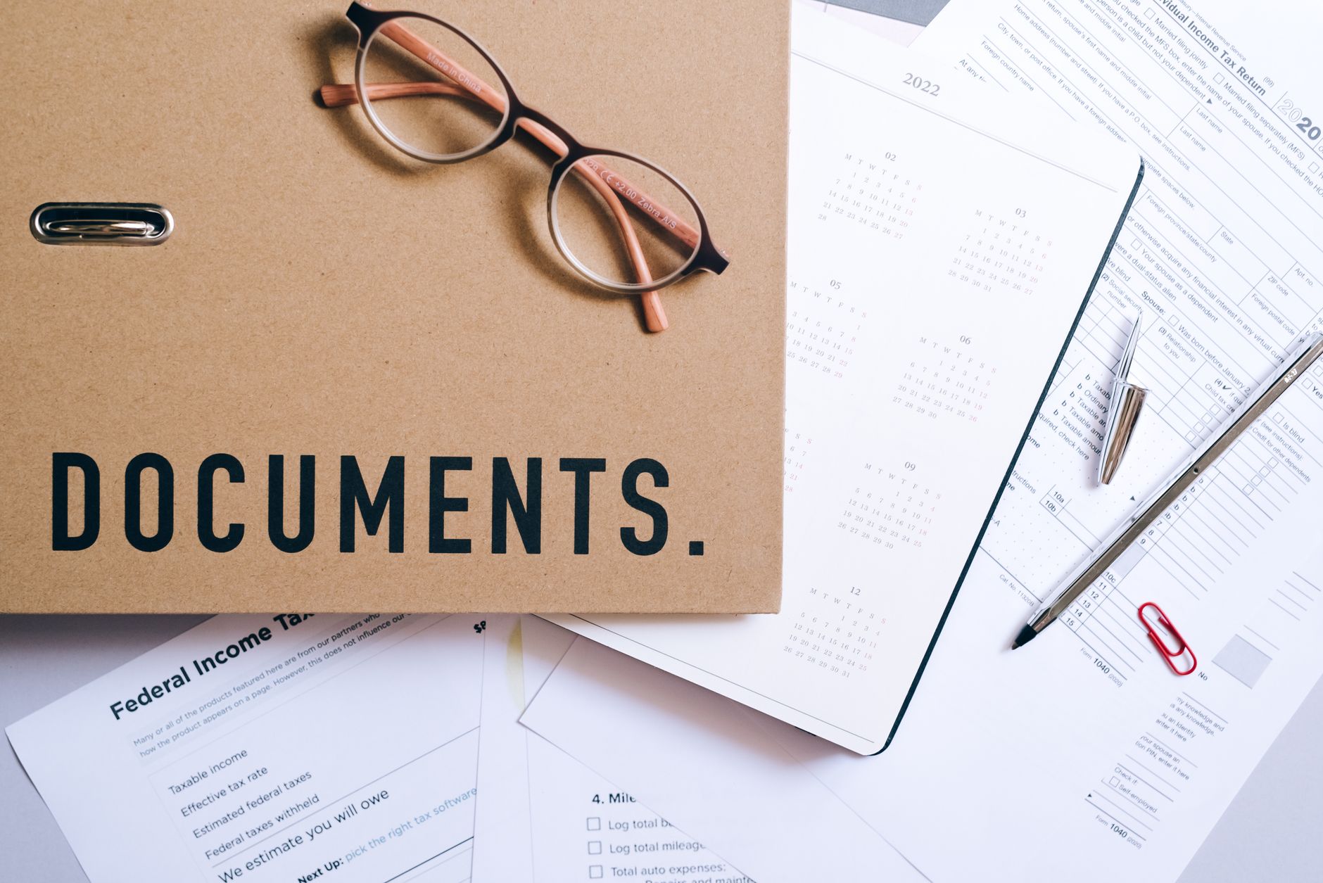 Flat lay of office documents, a calendar and eyeglasses on a desk