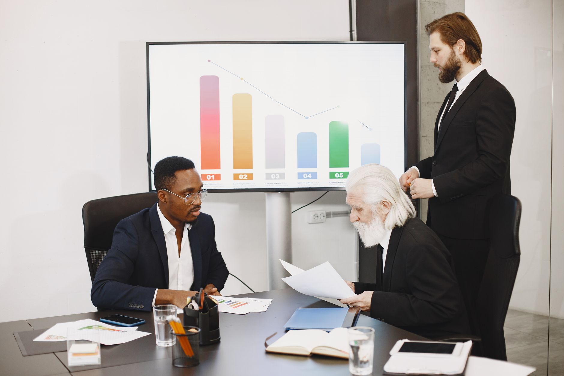 Three businessmen discussing financial data in a modern office setting with charts