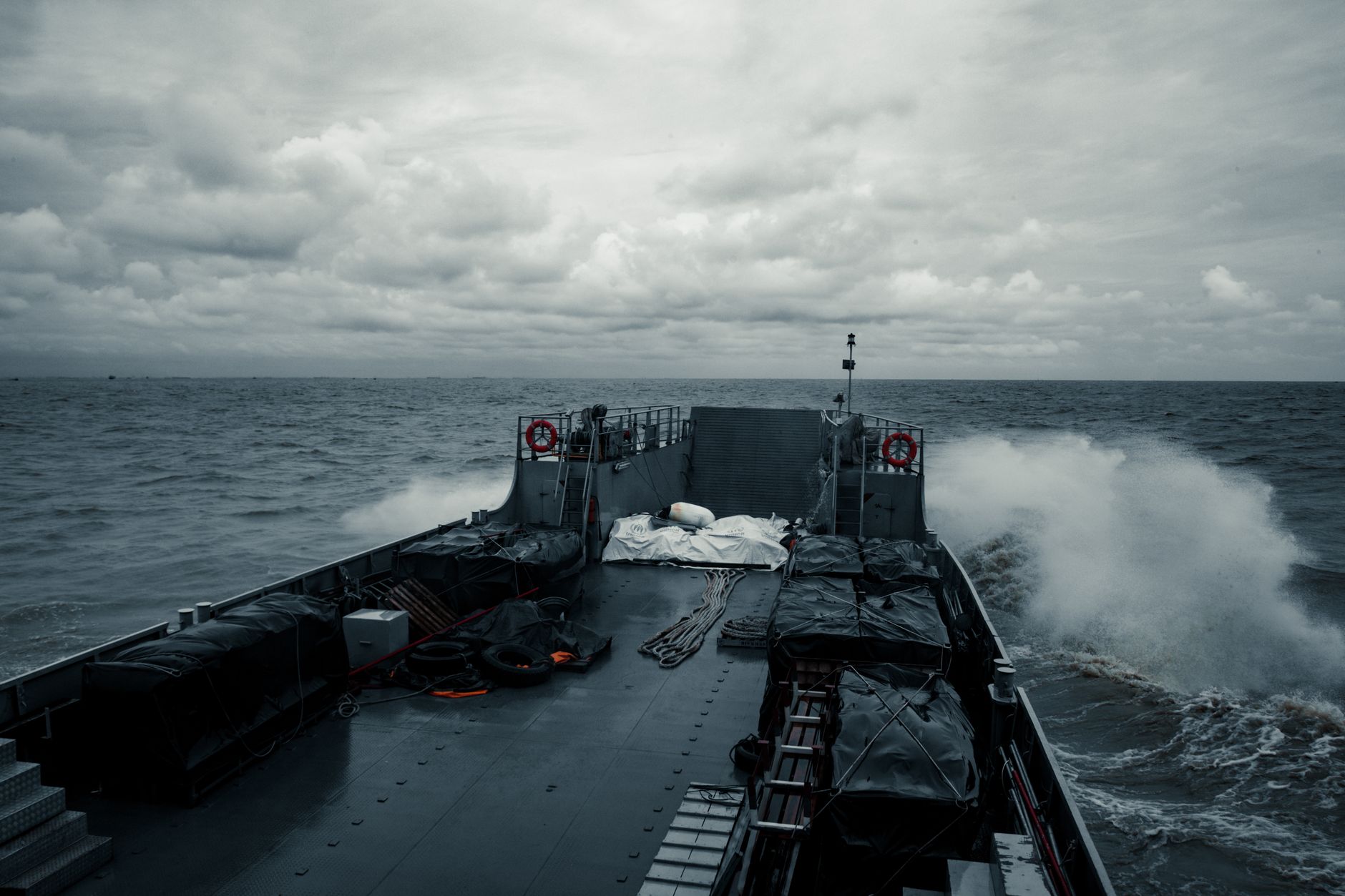 A military ship cruising through choppy ocean waters under a cloudy sky