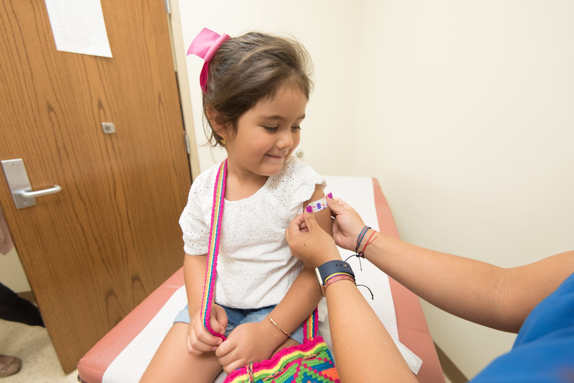 A young girl receives a band-aid after a vaccination at a clinic