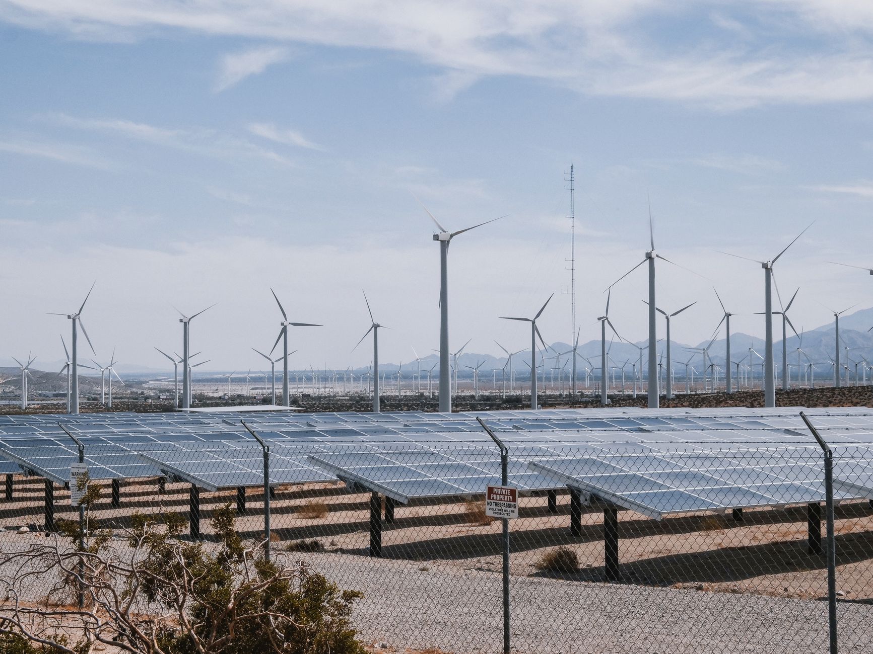 A renewable energy farm with wind turbines and solar panels under a clear sky