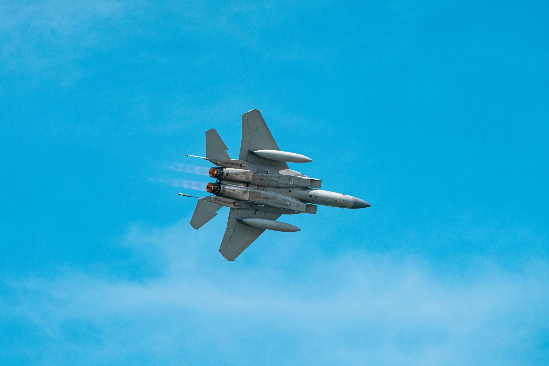 A military jet aircraft flying through a clear blue sky