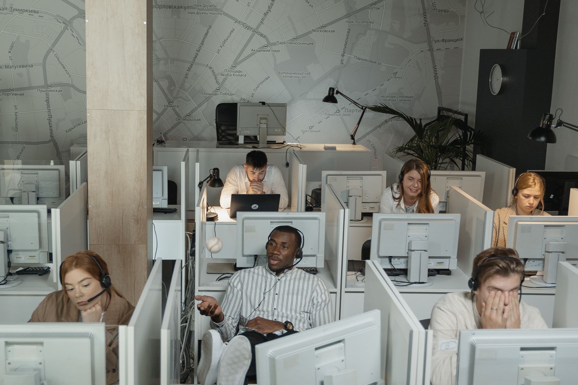 A group of employees working with computers and headsets in office cubicles