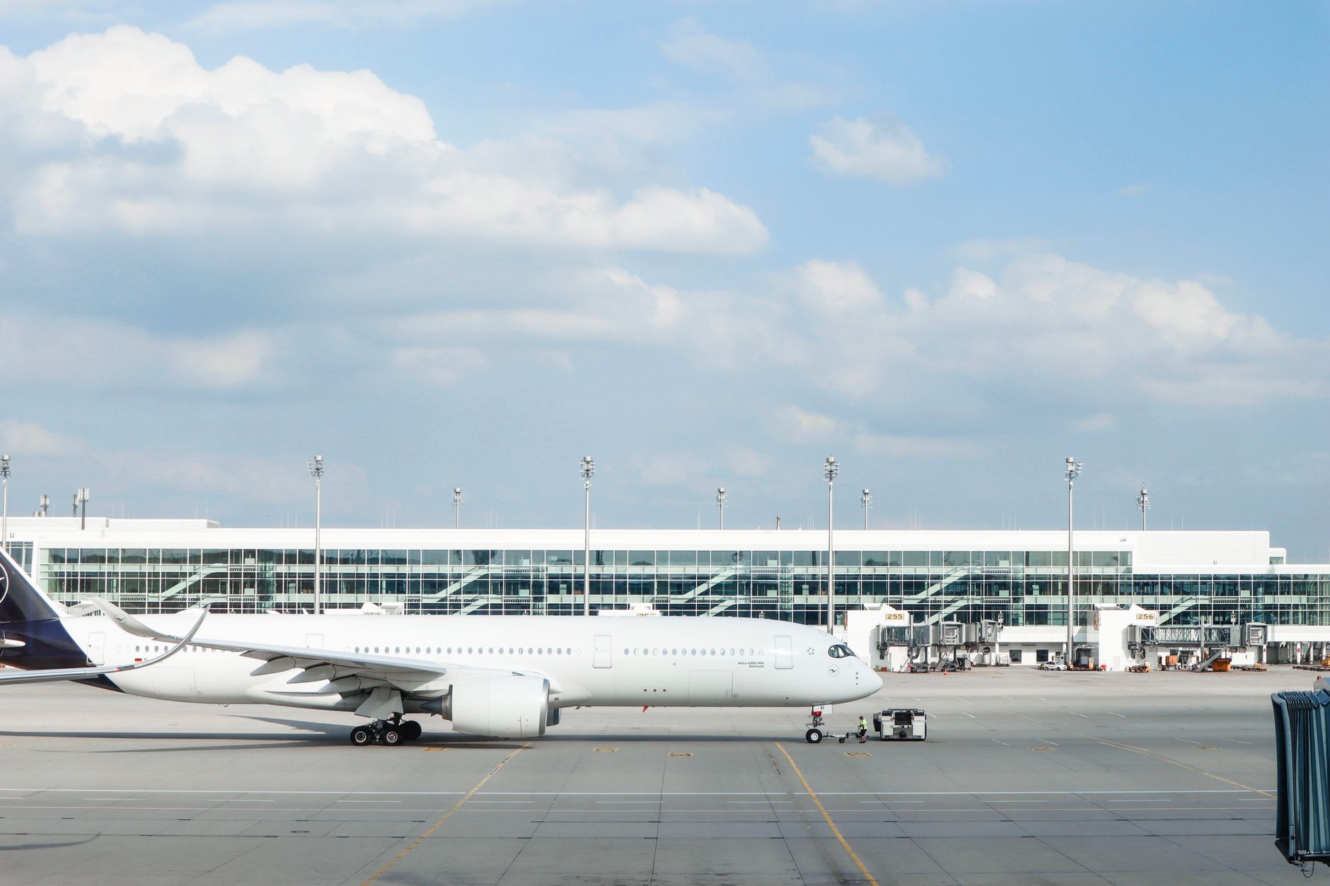A widebody aircraft parked at an airport gate during a clear day, with the terminal building visible