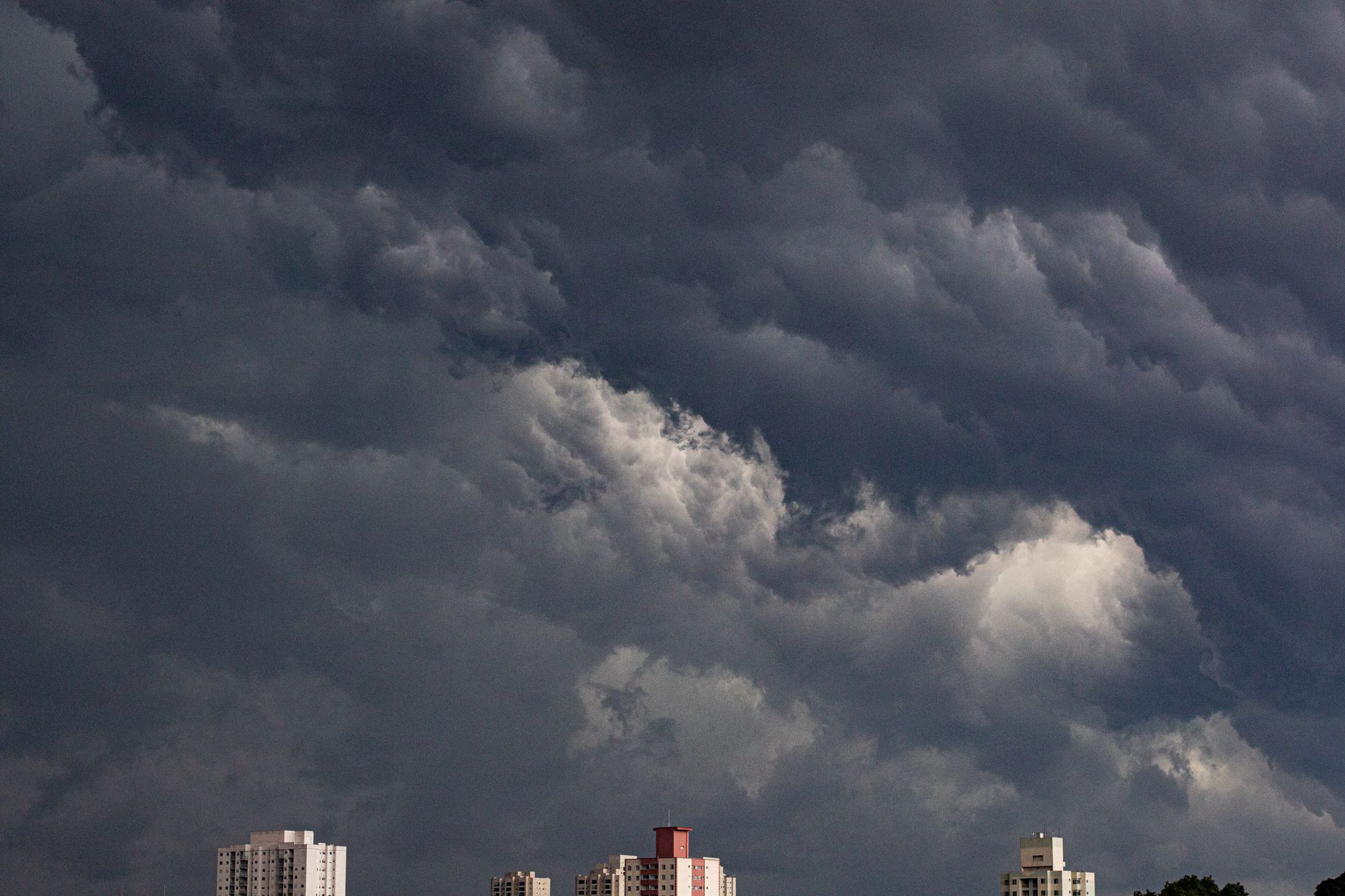 Dark storm clouds looming over city buildings in a dramatic, rain-heavy sky