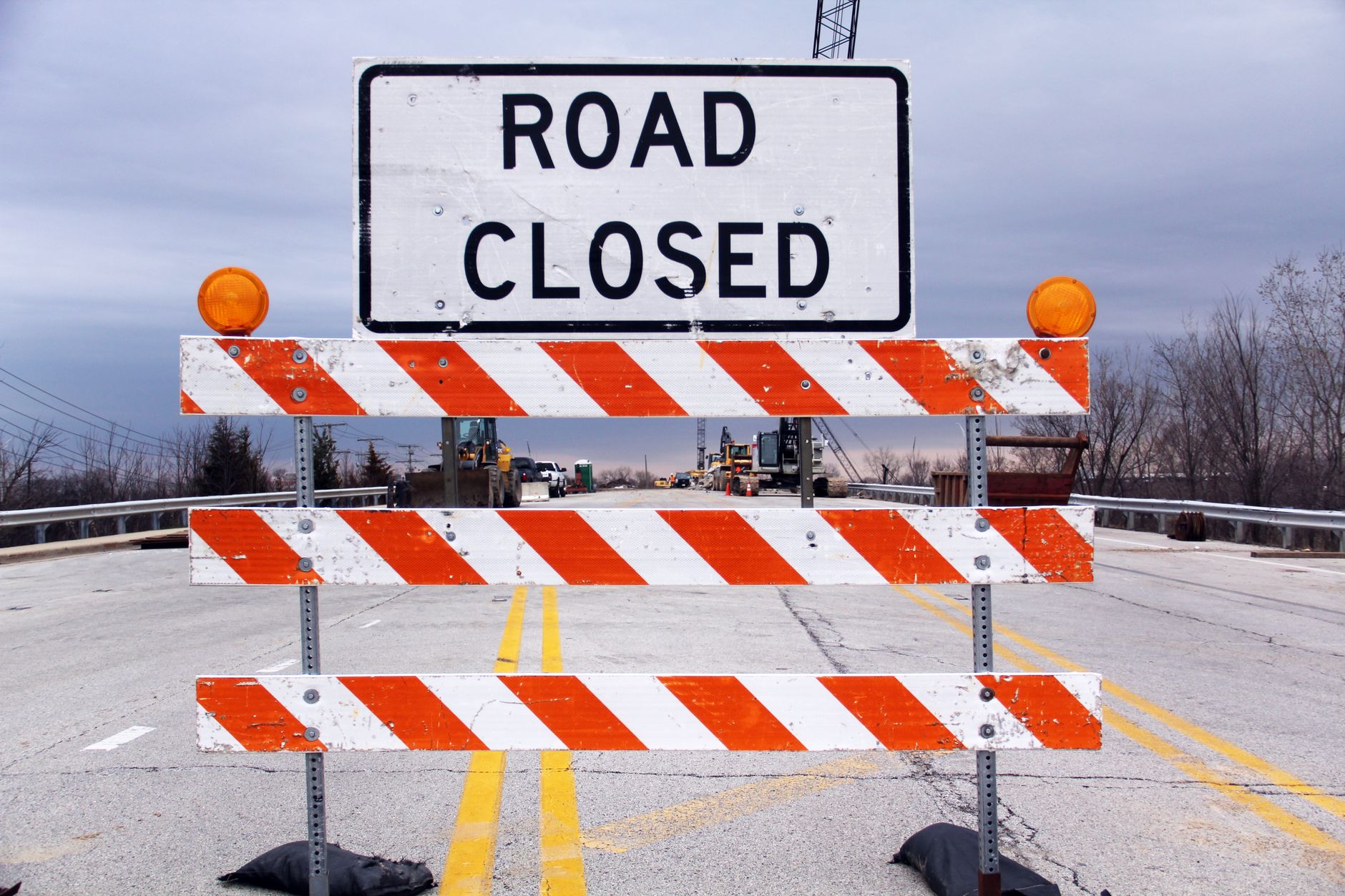 A road closed sign with barricade on a highway