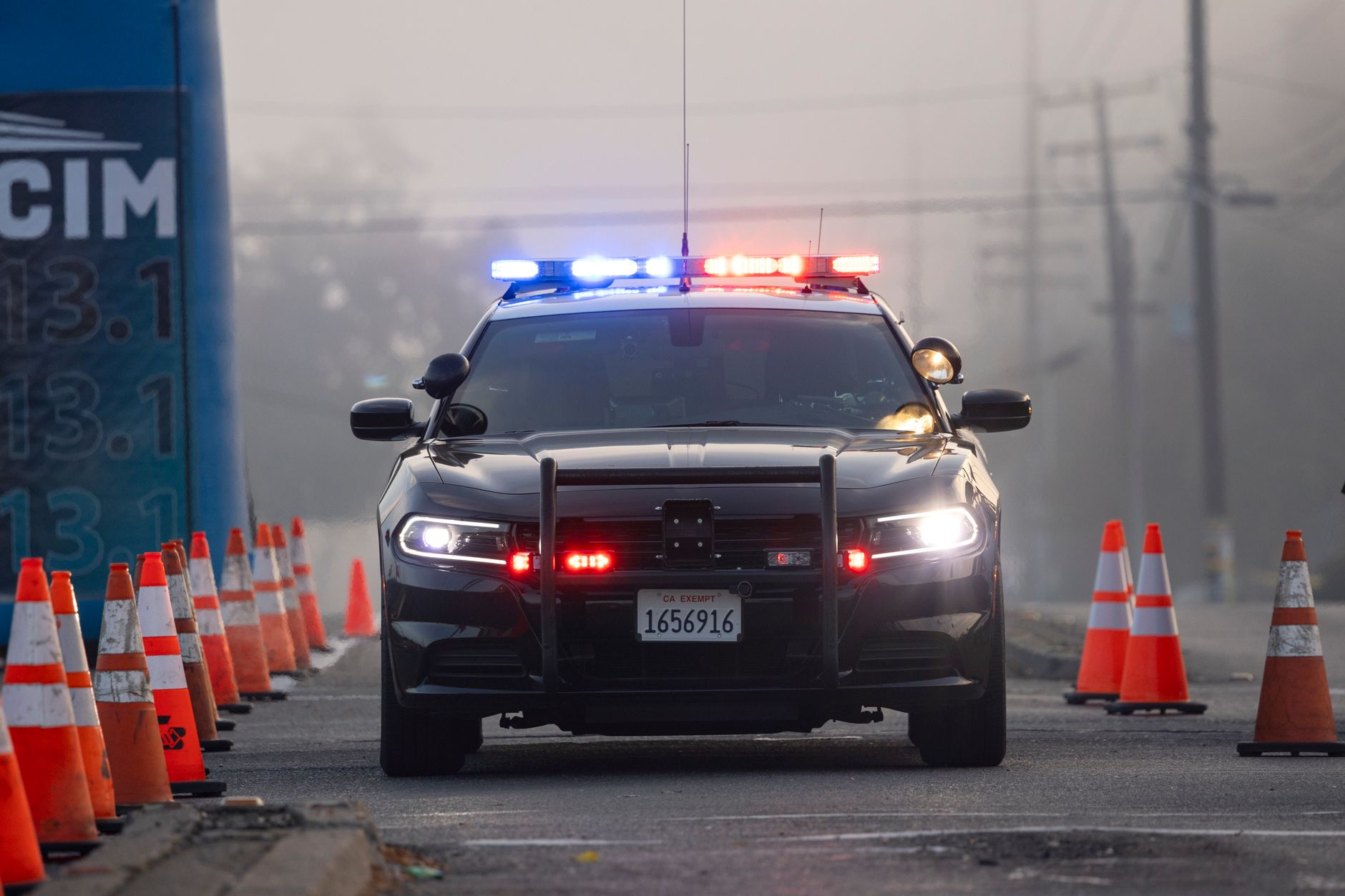 A police car parked at a roadside checkpoint marked with traffic cones