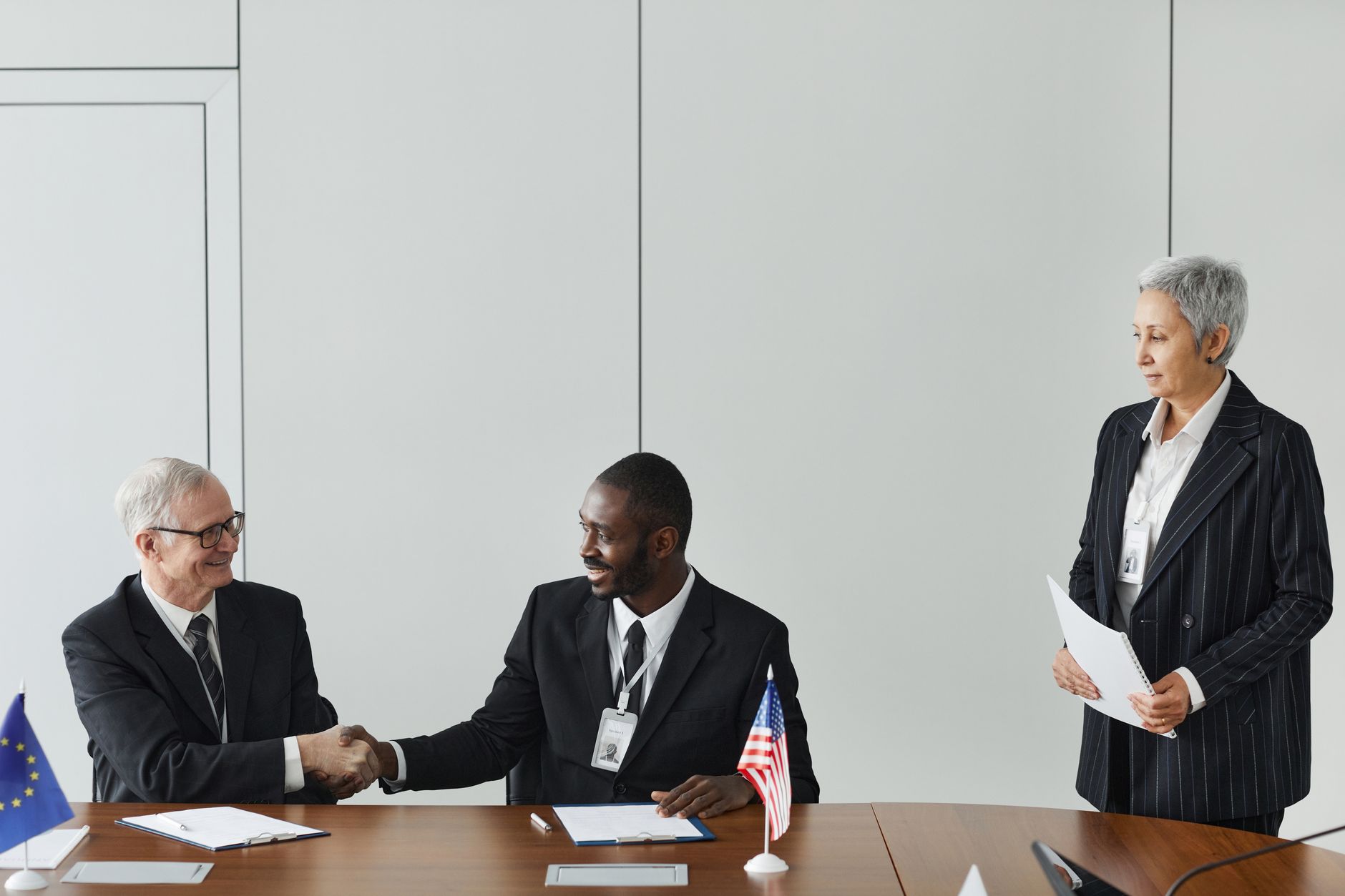 A multinational business meeting with an agreement signing and national flags