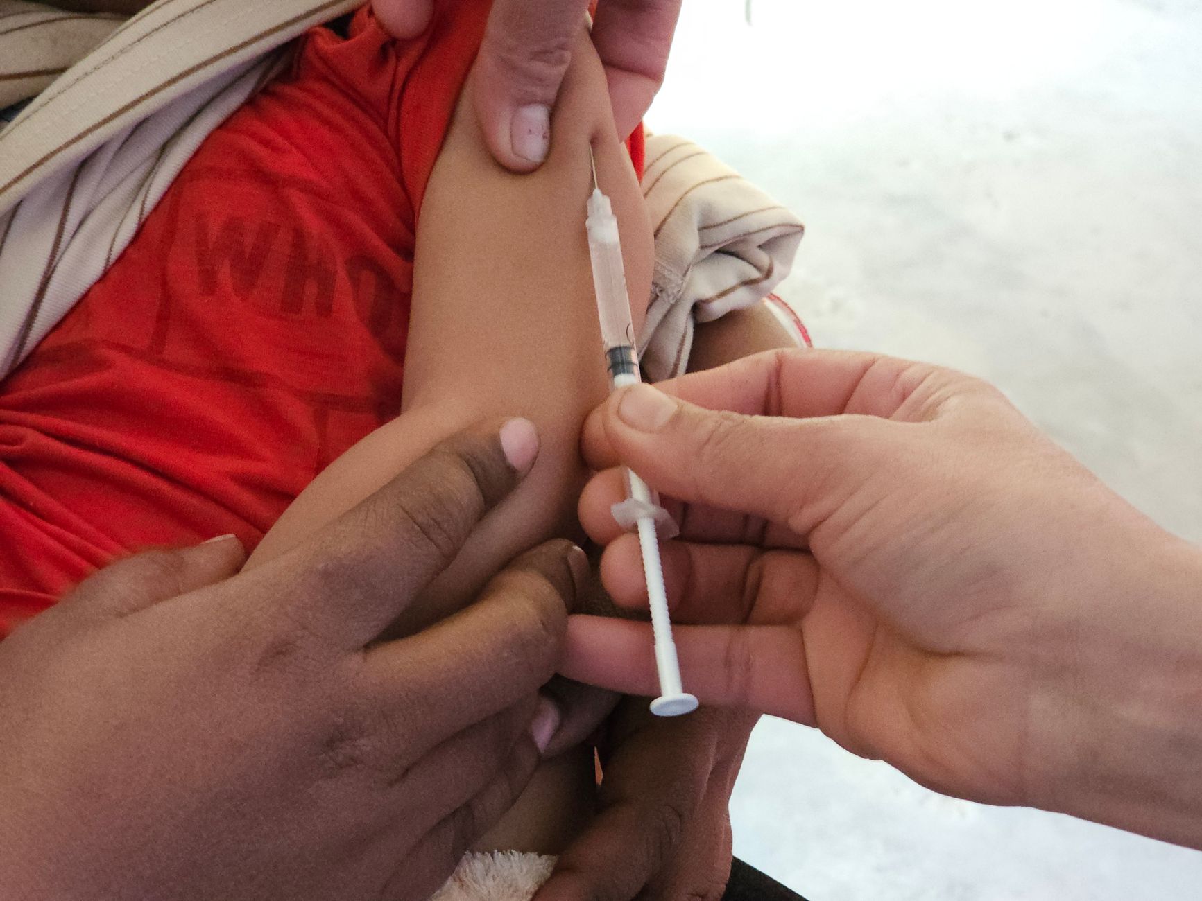 A child getting a vaccination shot administered by a healthcare professional indoors